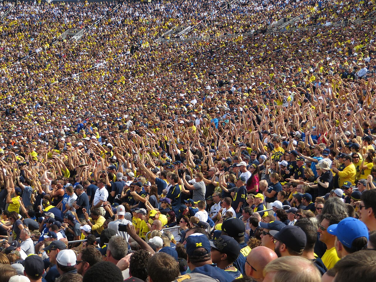 Tusentals Michigan-fans står tätt tillsammans på läktaren och gör vågen i Big House